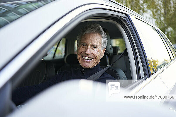 Happy senior man sitting in car