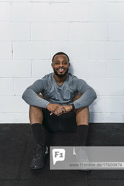 Smiling young athlete sitting in front of white wall