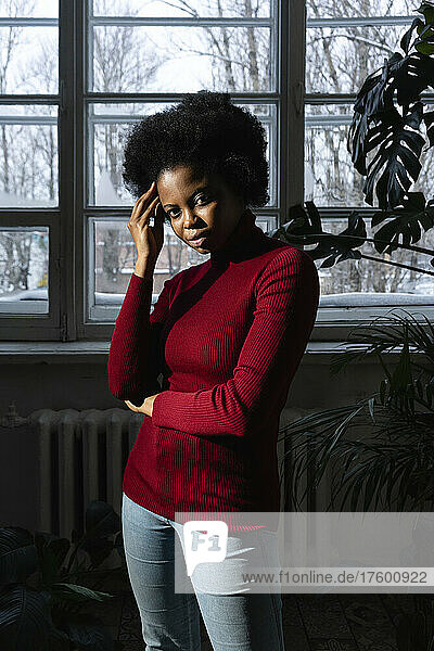 Junge Afro-Frau steht zu Hause vor dem Fenster