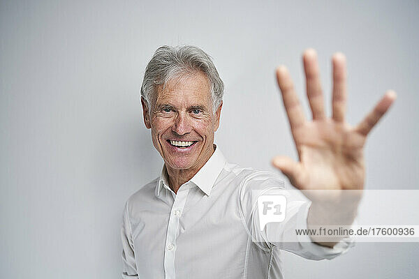 Happy businessman doing stop gesture against white background