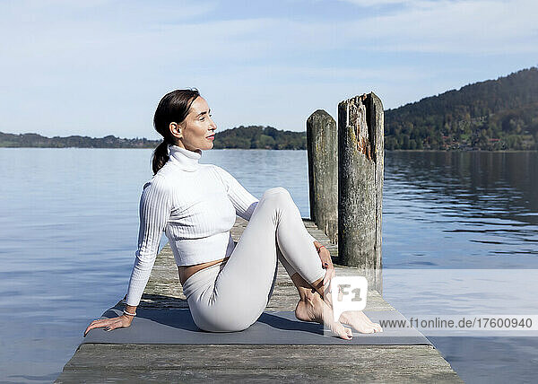 Active woman meditating on jetty