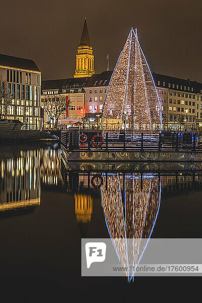 Germany  Schleswig-Holstein  Kiel  Large Christmas tree reflecting in city canal at night