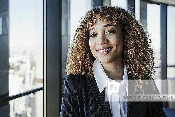 Happy businesswoman with curly hair in office