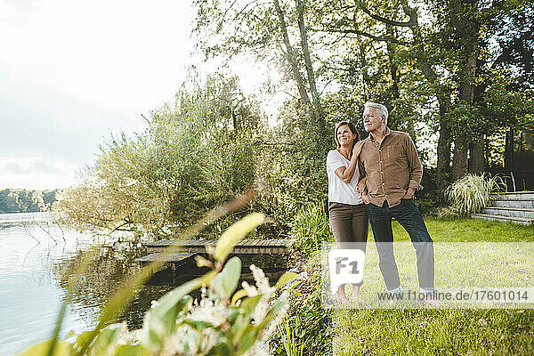 Senior man with woman standing by lake in garden