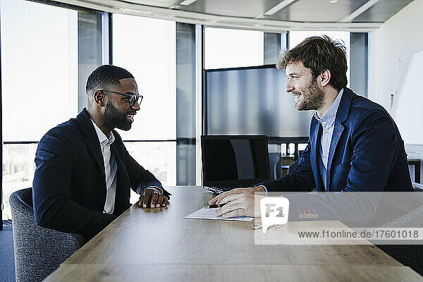 Smiling businessman talking with client in office