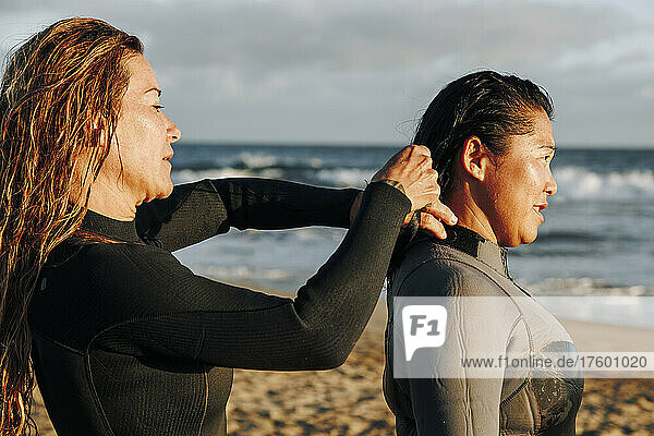 Woman assisting surfer putting on wetsuit at beach  Gran Canaria  Canary Islands