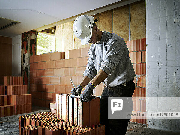 Bricklayer marking on bricks working at construction site