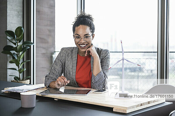 Happy businesswoman with hand on chin at work place