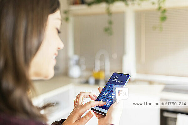 Young woman using smart home application on mobile phone at home