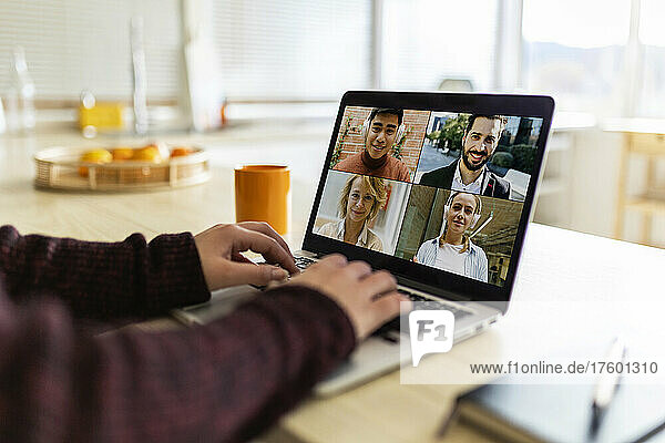 Working woman doing video conference with business colleagues on laptop at home