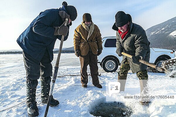 Eisfischen  Ein Fischer gräbt ein Loch in das Eis  das sich auf dem Baikalsee gebildet hat  um in der Region Severo Baikal zu fischen  Sibirien  Russland  Europa