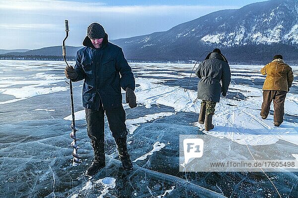 Ice fishing  A young fisherman digging a hole in the ice formed over Lake Baikal to fish  Lake Baikal  Severo Baikalsk  Siberia  Russia  Asia  Europe