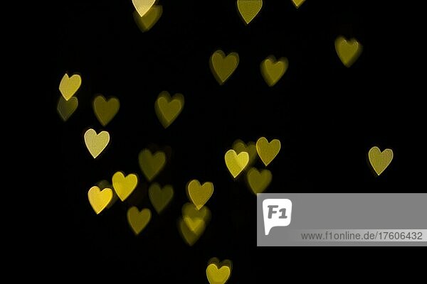 Lichteffekt mit gelben Herzen vor schwarzem Hintergrund  Bokeh