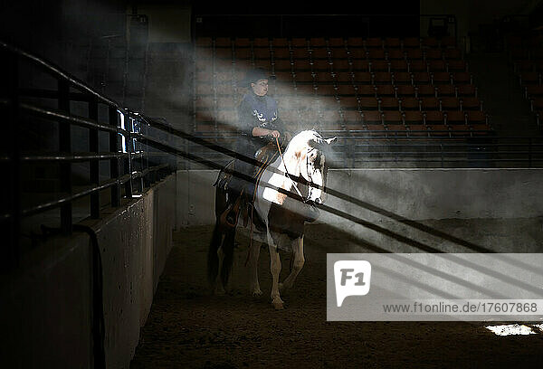 Young cowboy on wild mustang competes in horse show; Reno,  Nevada,  United States of America