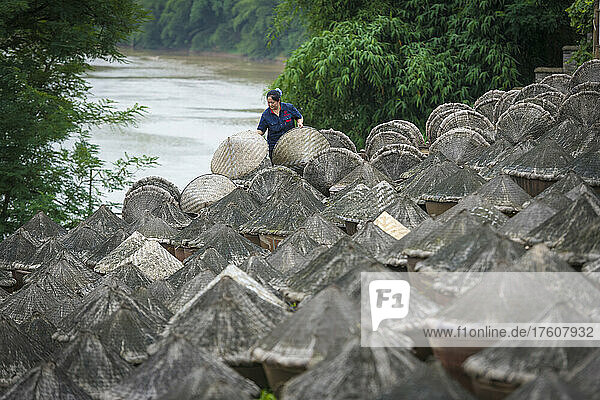 Frau  die sich um Töpfe mit traditionell hergestellter Sojasauce kümmert  auf dem Land am Fluss in China; Sichuan  China
