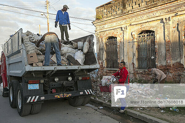 In der Innenstadt von Cienfuegos  Kuba  sammeln mehrere Männer den Müll von der Straße auf und legen ihn in einen Müllwagen; Cienfuegos  Kuba