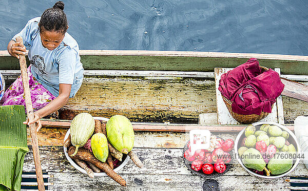 Woman selling fruit from canoe in Sewa Bay in the China Strait of Papua New Guinea; Milne Bay Province,  Papua New Guinea