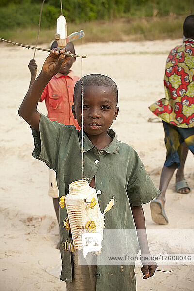 A boy poses with a plastic bottle he turned into a toy car.; Lower Zaire River  near Luozi  Democratic Republic of the Congo.
