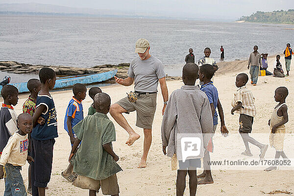 Skip spielt mit einem Fußball aus Schnüren und Klebeband mit einheimischen Jungen; Unterer Kongo-Fluss  Demokratische Republik Kongo.