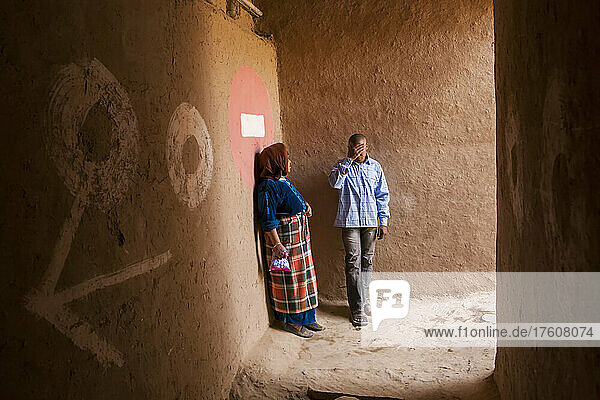 In Merzouga unterhalten sich ein Mann und eine Frau in einer Gasse zwischen Häusern; Merzouga  Marokko