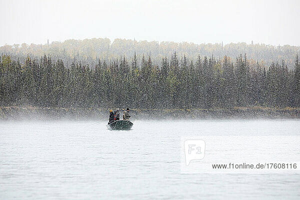 People fishing for rainbow trout from a boat in a late autumn snowstorm on the Kenai River; Sterling,  Alaska,  United States of America
