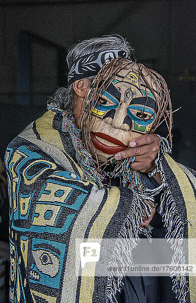 Mann steht in eine Decke mit indianischem Muster gehüllt und hält eine Maske  um sein Gesicht zu verdecken; Hoonah  Alaska  Vereinigte Staaten von Amerika