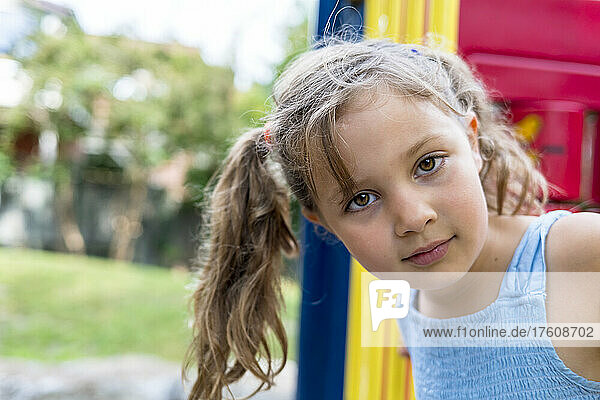 Outdoor portrait of a young girl standing on colourful playground equipment; Toronto  Ontario  Canada