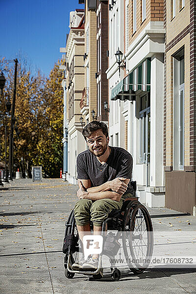 Außenporträt eines jungen querschnittsgelähmten Mannes in seinem Rollstuhl auf einem städtischen Gehweg an einem schönen Herbsttag; Edmonton  Alberta  Kanada