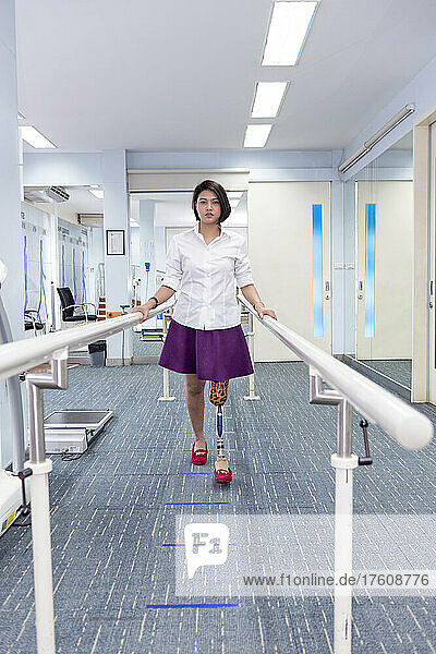 Junge Frau mit Beinprothese in Therapie  geht mit Handläufen; Bangkok  Thailand