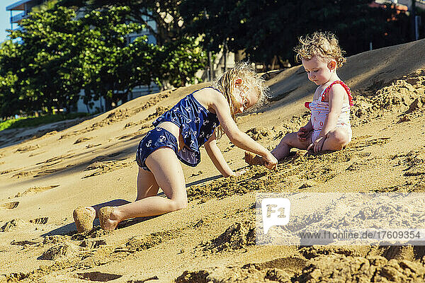 Two young girls on Ka'anapali Beach playing in the sand together; Ka'anapali  Maui  Hawaii  United States of America