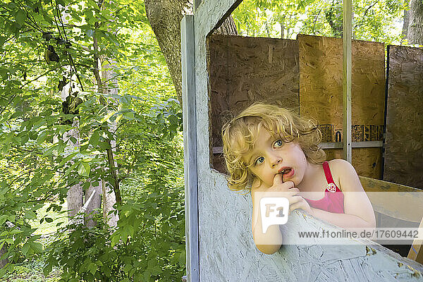 20 month old toddler girl relaxes in her backyard treehouse.; Cabin John  Maryland.