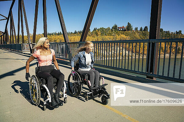 Zwei junge querschnittsgelähmte Frauen in ihren Rollstühlen in einem Park an einem schönen Herbsttag; Edmonton  Alberta  Kanada