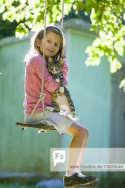 Sechsjähriges Mädchen und ihr Kätzchen auf einer Gartenschaukel im Sommer; Cabin John  Maryland.