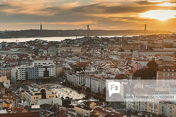 Überblick über die Stadt Lissabon  mit den pastellfarbenen Gebäuden der Altstadt  der Tejo-Mündung und der Hängebrücke Ponte 25 de Abril bei Sonnenuntergang; Lissabon  Portugal