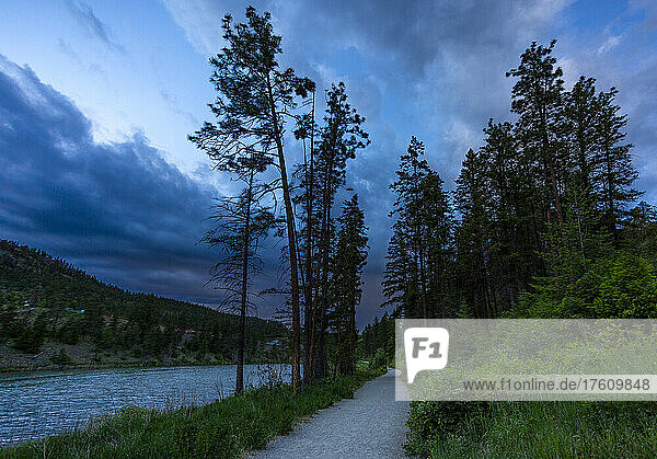 Pfad neben einem stillen Gewässer in einem Waldgebiet in der Abenddämmerung; Kelowna  British Columbia  Kanada