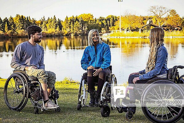 Gruppe von drei jungen Querschnittsgelähmten in ihren Rollstühlen  die an einem schönen Herbsttag gemeinsam einen Park besuchen; Edmonton  Alberta  Kanada