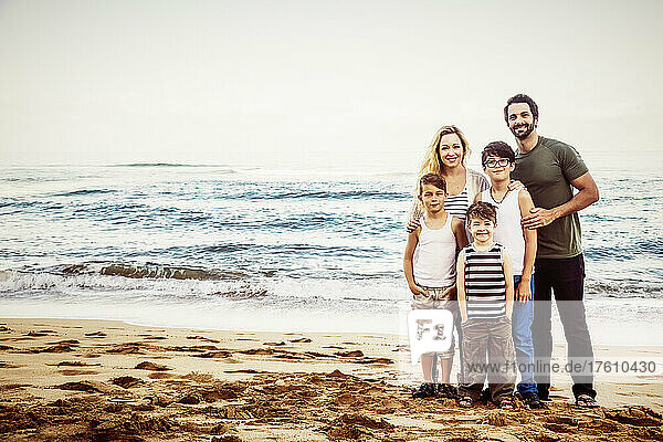 Portrait of a family with three boys standing on Ka'anapali Beach with the ocean in the background; Ka'anapali  Maui  Hawaii  United States of America