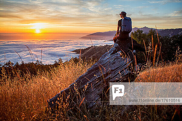 Eine junge Frau betrachtet den Sonnenuntergang über den Wolken in Big Sur  Kalifornien  USA.