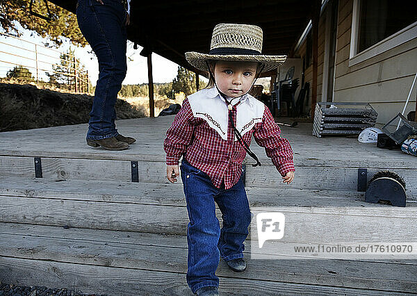 Young cowgirl heads to the barn to watch the horses; Prineville  Oregon  United States of America