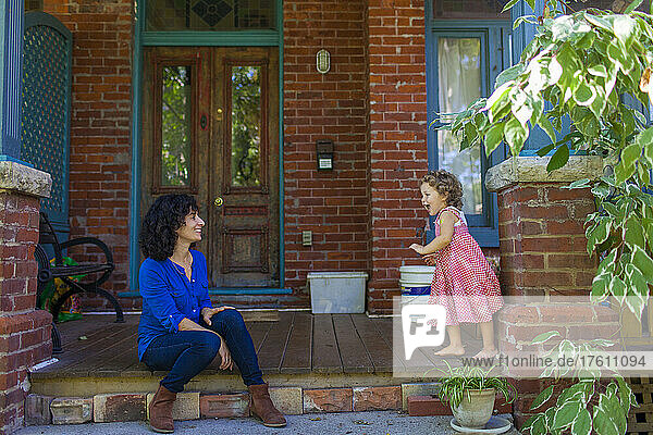 Mutter und kleine Tochter sitzen vor der Haustür ihres Hauses und verbringen Zeit miteinander; Toronto  Ontario  Kanada
