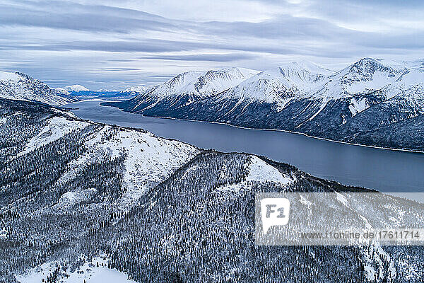 Aerial landscape image of Tutshi Lake on a grey day with dramatic clouds with snow capped mountains in winter; Yukon  Canada
