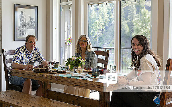 Family with a young adult daughter sitting for a meal at the kitchen table; Kelowna  British Columbia  Canada