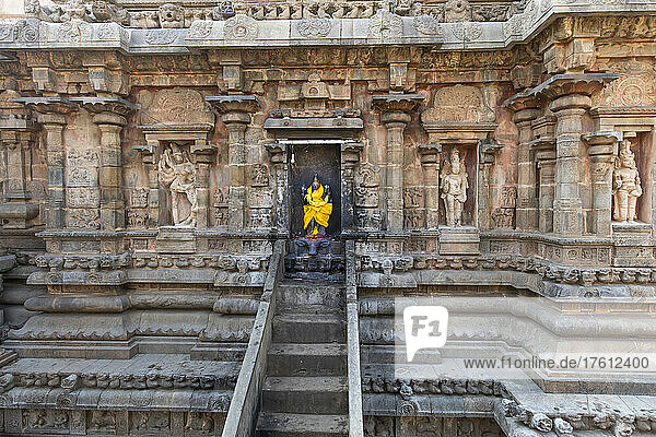 Treppe  die zu einer Nische mit einer in leuchtend gelbe Seide gehüllten Statue einer Hindu-Gottheit in einer Steinwand des Airavatesvara-Tempels aus der dravidischen Chola-Ära führt; Darasuram  Tamil Nadu  Indien