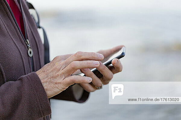 Nahaufnahme der Hände einer Frau  die beim Wandern ein Smartphone benutzt; British Columbia  Kanada