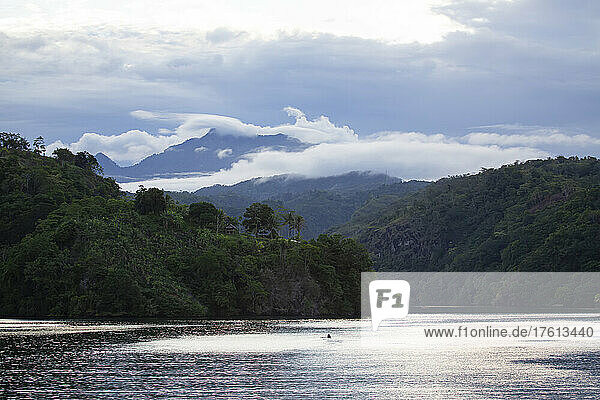 Clouds swirling around mountains of the Tufi tropical sea fjord with outrigger canoe on the Cape Nelson peninsula; Tufi  Oro Province  Papua New Guinea
