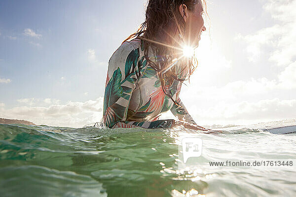 Ein Surfer mit Sonnenschein wartet auf die Wellen im klaren blauen Wasser.