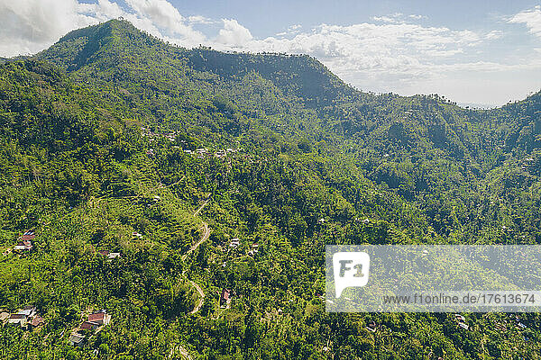 Überblick über den Berghang mit Häusern auf dem Berg Abang  mit blauem  bewölktem Himmel und üppiger Vegetation; Abang  Kabupaten Karangasem  Bangli Regency  Bali  Indonesien
