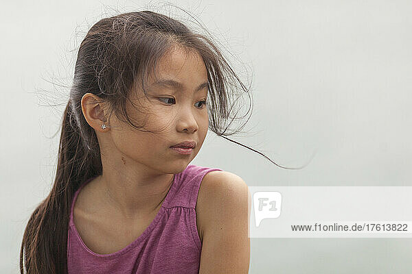 Porträt eines jungen Mädchens mit langen brünetten  vom Wind zerzausten Haaren und einem rosa Hemd; Hongkong  China
