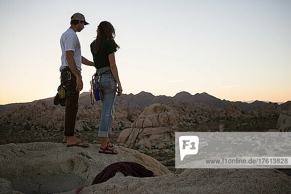 A young couple take in the sunset after climbing The Eye route on Cyclops Rock in Joshua Tree National Park.