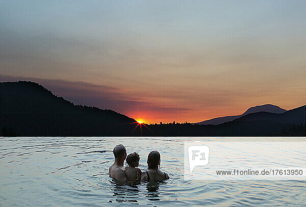 Junge Familie beobachtet einen Sonnenuntergang beim Schwimmen in einem See  Ruby Lake an der Sunshine Coast von BC  Kanada; British Columbia  Kanada